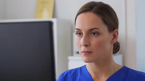 Hispanic doctor works with technology at her desk in a busy hospital office