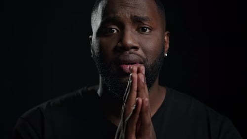 Man Clasping Hands Together on Black Background
