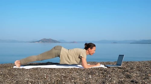 Woman Doing Plank Exercise at Beach with Laptop