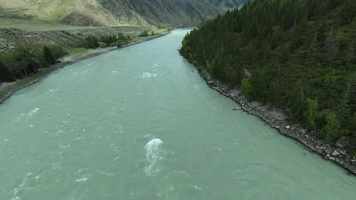 Drone flying over turquoise river flows in intermountains.