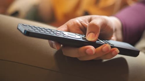 Hand Holding a Remote Control While Sitting on a Couch
