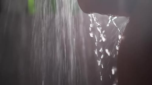 Water Cascades Forcefully from Dark Rock Ledge