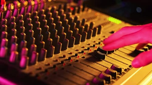 Hand Settings Volume Level Controls on Mixing Console Faders Neon Light CloseUp