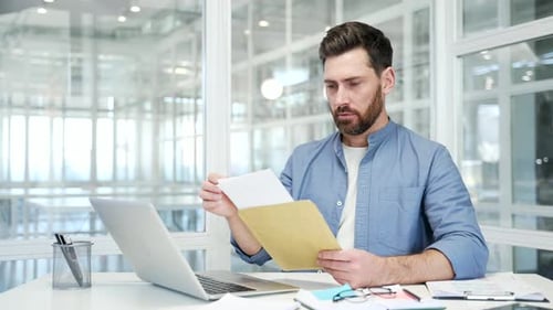 Upset disappointed businessman reading a letter with bad news sitting in a business office. Worried