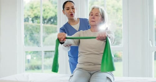 Caregiver Helping Senior Woman with Resistance Band Exercise