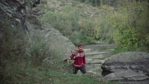 Man with Backpack Hiking along Rocky Forest Riverbank