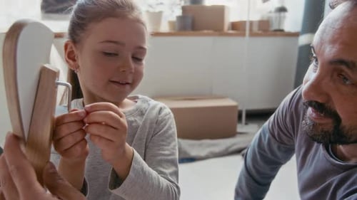 Father and Daughter Fixing Chair Part while Little Girl Rotating Handtool