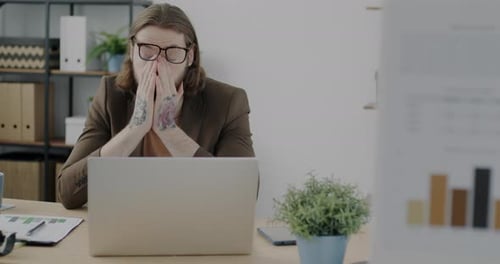 Frustrated Businessman Working with Laptop and Rubbing Eyes Feeling Tired and Demotivated in Office
