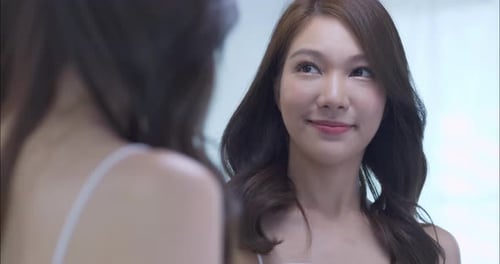 Beautiful Woman Styles Hair in Mirror