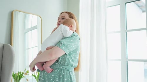 Mother Holding Newborn Infant in Bright Home Interior