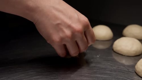 Close Up of Hands Gently Shaping Smooth Dough Balls on a Stainless Steel Countertop Demonstrating