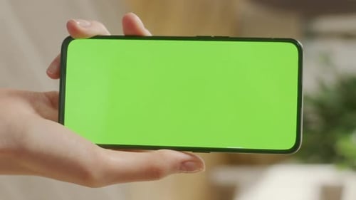 Back View of Woman Holding Chroma Key Green Screen Smartphone Watching Content Without Touching or