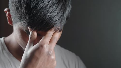 Une personne exprime une profonde frustration dans une pièce faiblement éclairée