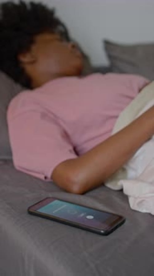 Drowsy Black Woman Ignoring Alarm Clock Ringing on Smartphone