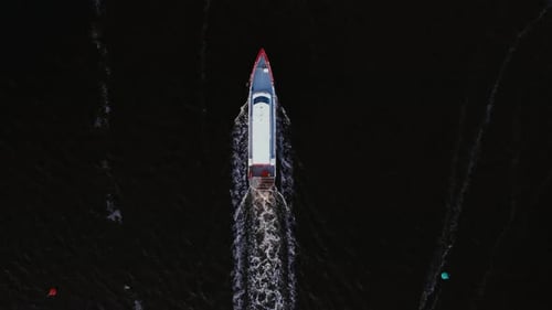 Aerial view of a boat navigating through calm waters at dusk