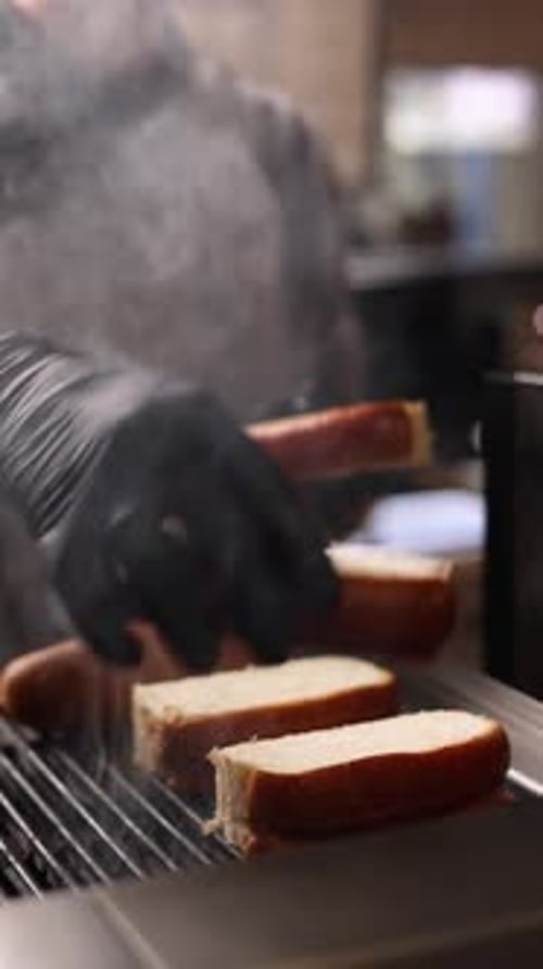 A chef prepares delicious hot dogs in a restaurant.