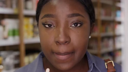African American Girl Testing Lip Balm in front of Mirror in Cosmetics Shop
