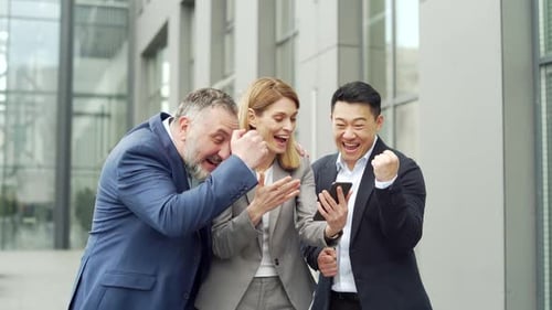 group of colleagues fellow employees read good news looking at smartphone. Happy team rejoices about