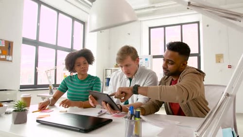 Happy multiethnic business team brainstorming with tablet computer in modern office
