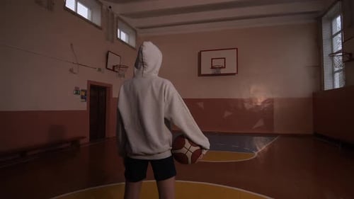Jeune joueur de basket-ball tenant un ballon dans un gymnase vide