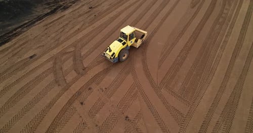 A Road Construction Roller Compacts Sand Before Laying New Asphalt