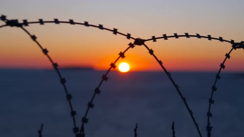 Fence Silhouette with Sunset Over Ocean Horizon