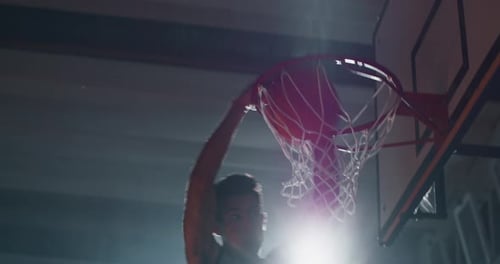 Filmmusik Zeitlupenaufnahme eines jungen professionellen männlichen Spielers, der während eines Basses einen Slam Dunk macht