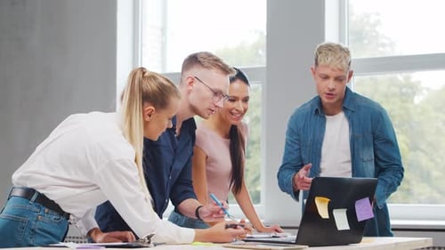 Team of Young Startupers is Working at the Table in the Office Discussing the Strategy and