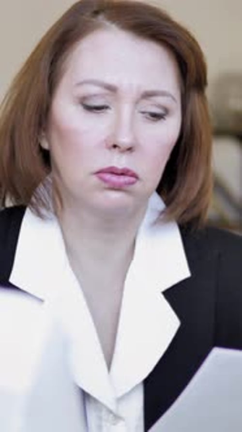 Serious Woman Reviews Documents in Business Attire