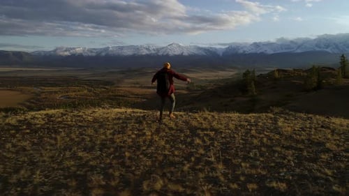 Successful modern traveler reaching mountain peak with victory gesture in national park