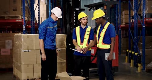 Warehouse Workers Discussing Inventory Near Forklift Indoors