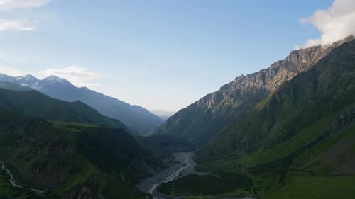 Aerial View of the Caucasus Mountains with River Valley and Green Hills Mountain Range with Sharp