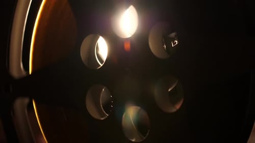 Abstract view of a cinema reel as the projector lights shine through the reel as it rotates.