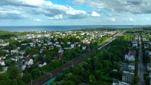Vue aérienne de Gdynia Orłowo, présentant des quartiers résidentiels entourés d'une végétation luxuriante, avec un rail
