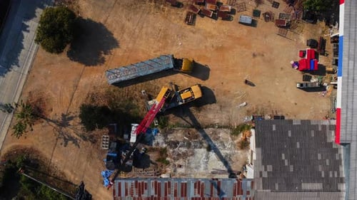 Mobile crane stands waiting to lift steel at a warehouse. Crane operators and mobile cranes