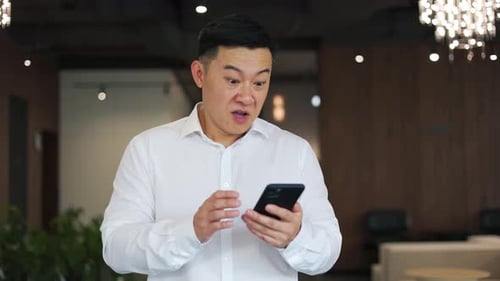 Asian Man Celebrating Success When Seeing Rising Charts at Stock Exchange Market