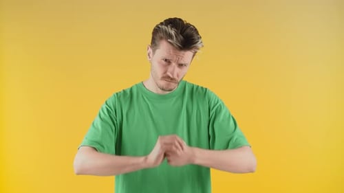 A Young Man Stands in Front of the Camera and Shows a Gesture of Aggression A Man in a Green Tshirt