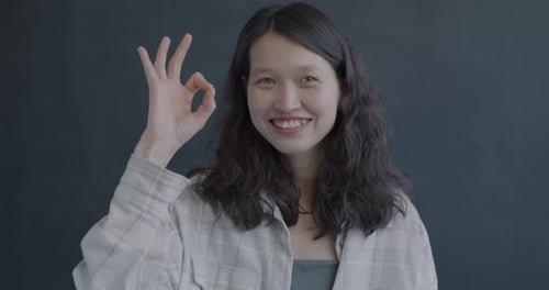 Smiling Young Woman Shows OK Hand Gesture