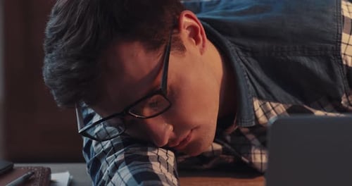 Une personne concentrée travaillant à un bureau de travail entourée d'un verre et de notes