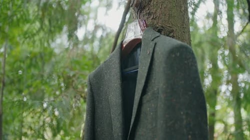 Suit jacket hanging from tree trunk outdoors