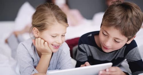 Children Watching Tablet on Bed Together