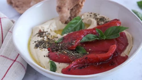 Pita Bread Dipping into Hummus with Roasted Peppers