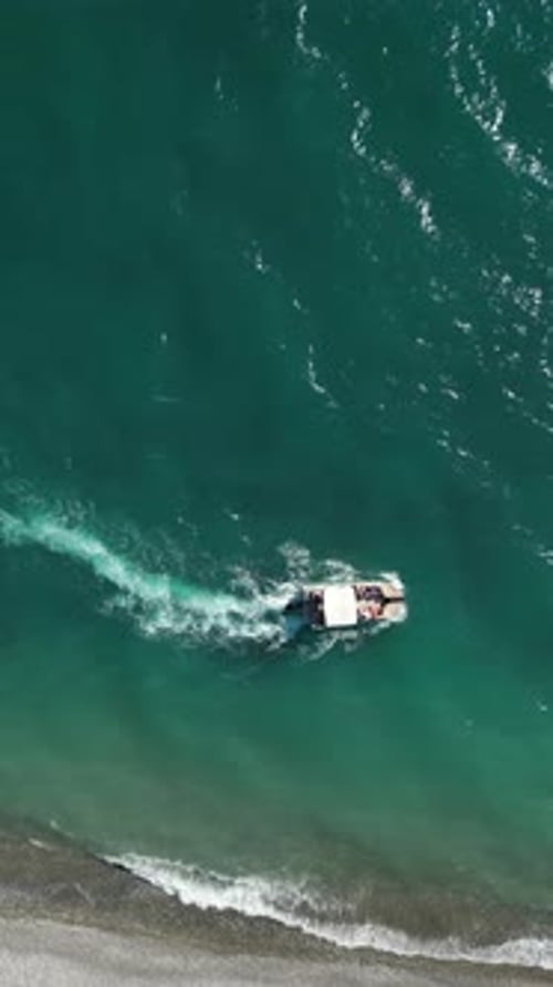 Aerial Video of a White Boat with Tourists Rides on the Sea Near Pebble Beach Vertical Video