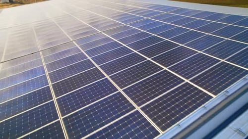 Aerial drone view of multiple solar panels on the roof of a manufacturing building. Ecology thematic