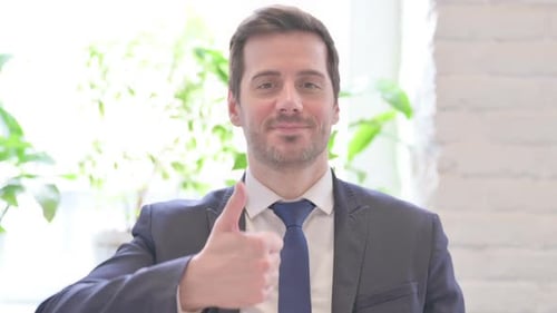 Thumbs Up By Excited Young Businessman in Office