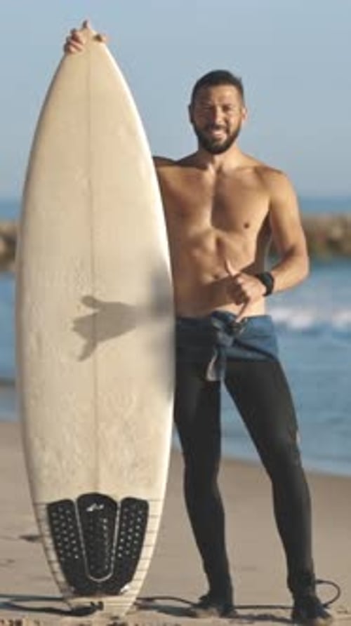 Man Holding Surfboard on Sunny Beach Day