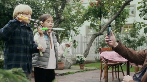 Grandfather Films Kids Blowing Bubbles in Backyard