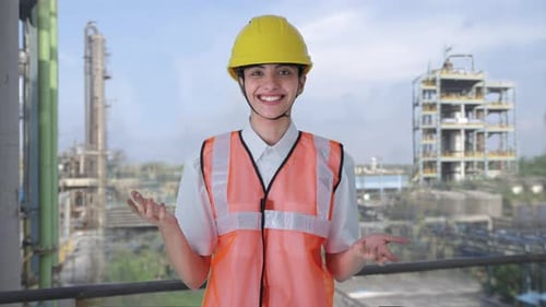 Smiling Engineer Gesturing at Industrial Plant