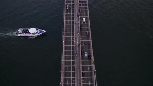 Ferry driving under the brooklyn bridge revealing the city downtown, in NYC, USA - tilt, Aerial