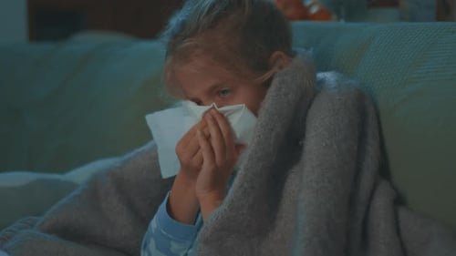 Ill Child Wipes Nose with Tissue at Home